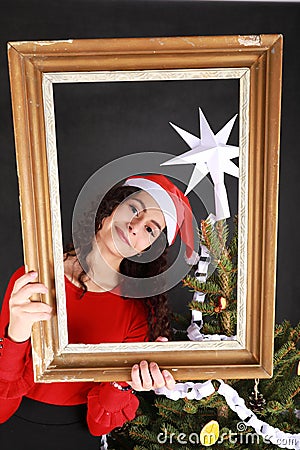 Smiling teen girl in red Christmas cap behind old frame Stock Photo