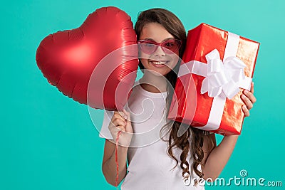 smiling teen girl in sunglasses hold gift box and valentines party heart balloon, happy childhood. Stock Photo