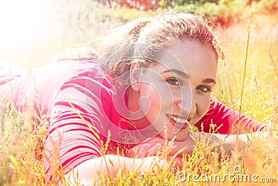 Smiling teenage girl resting in the grass, psychedelic colorful effects Stock Photo