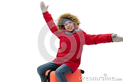 Smiling teenage traveler boy in warm winter clothes, sits on a suitcase, travels abroad, travelling on weekends getaway Stock Photo