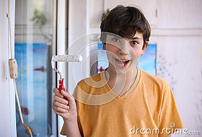 Smiling teenager boy with white paint roller and dirty face make repaint Stock Photo