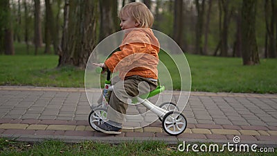 Smiling toddler making first try on bike. Happy boy riding on bicycle outdoors. Stock Photo