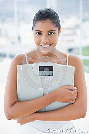 Smiling toned brunette holding scales Stock Photo