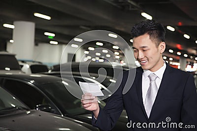 Smiling Traveler looking at ticket in airport parking lot Stock Photo