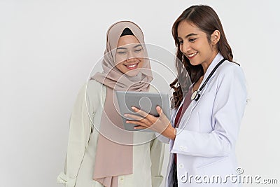 smiling veiled woman and doctor beautiful woman laughing while using tablet together Stock Photo