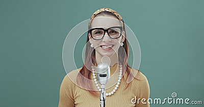 Smiling vintage style woman standing in front of a microphone Stock Photo