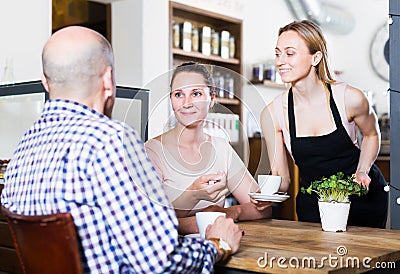smiling waiter girl brought cup of coffee for couple of different aged people Stock Photo