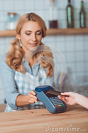 smiling waitress holding cardkey reader while customer paying Stock Photo