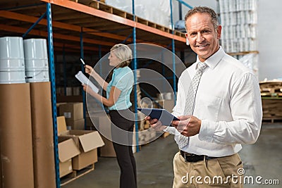 Smiling warehouse manager using tablet pc Stock Photo