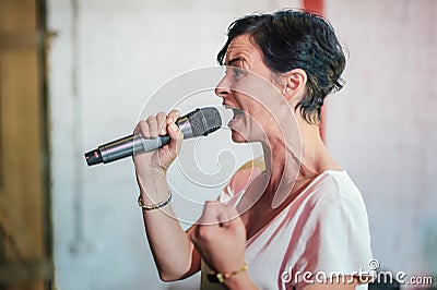 Smiling and witty stand up actor comedian on stage, talking and singing Stock Photo