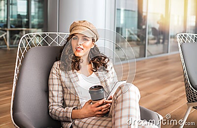 Smiling woman in airport cafe with cup of coffee. Stock Photo