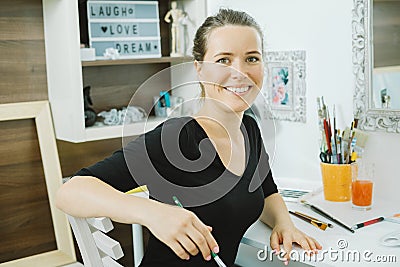 Smiling woman artist with paintbrush at the workplace Stock Photo