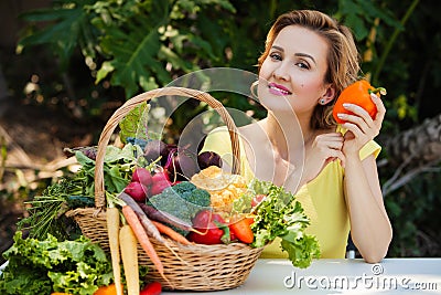 Smiling woman with basket full of vegetables outdoors. Healthy lifestyle. Stock Photo