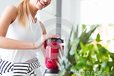 Smiling woman blending red smoothie Stock Photo