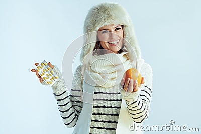 Smiling woman with blister pack of vitamins giving and orange Stock Photo