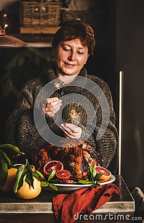 Smiling woman burning sparkles over Christmas dinner whole roasted turkey Stock Photo