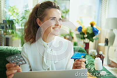 Smiling woman buying pharma in modern living room in sunny day Stock Photo