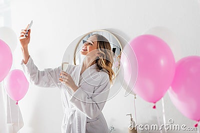 Smiling woman with champagne taking selfie Stock Photo