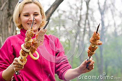 Smiling woman cooking kebabs over a BBQ fire Stock Photo