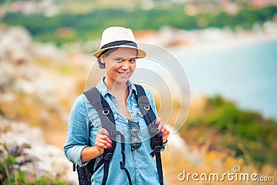 Smiling woman, hiker going on path, mountains with backpack. traveling and trekking on coastline Stock Photo