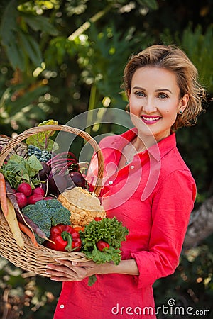 Smiling woman holding basket full of vegetables outdoors. Healthy lifestyle. Stock Photo