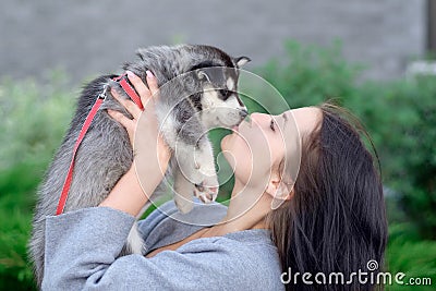 Smiling woman holding cute husky puppy Stock Photo