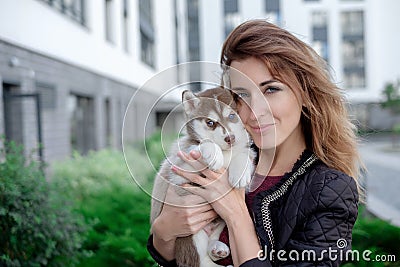 Smiling woman holding cute husky puppy Stock Photo