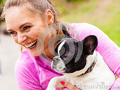 Smiling woman holding french bulldog outside Stock Photo