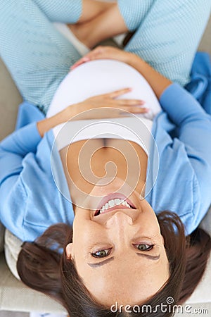 Smiling woman holding her pregnant belly posing at camera Stock Photo