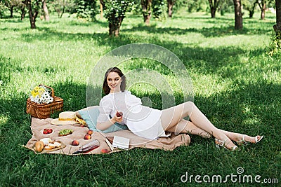 Smiling woman holding peach near books Stock Photo