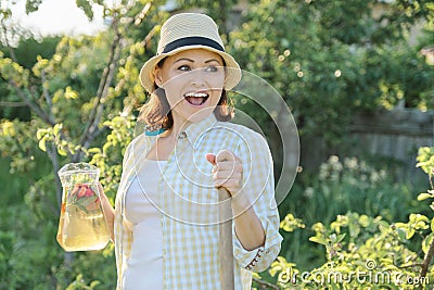 Smiling woman with jug of refreshing natural homemade drink in the summer garden Stock Photo