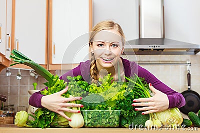 Smiling woman in kitchen with green vegetables Stock Photo