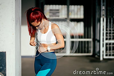 smiling woman listening to music and training doing exercises. Woman holding smartwatch and smartphone Stock Photo