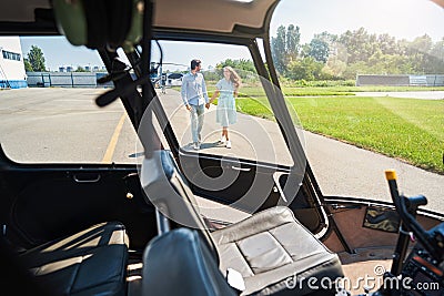 Smiling woman and man walking towards helicopter Stock Photo