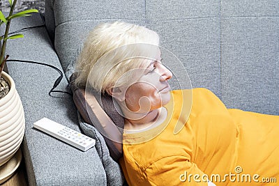 Smiling woman massaging her neck with a portable neck, back and lumbar massage pillow. Stock Photo