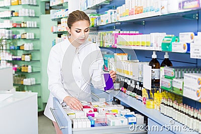 Woman pharmacist is attentively searching medicines in apothecary Stock Photo