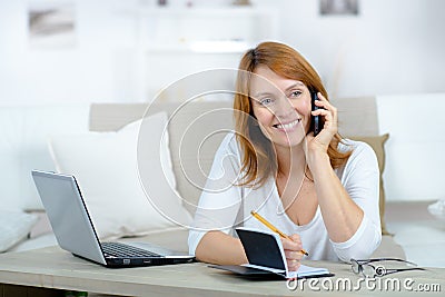 Smiling woman on phone call using laptop Stock Photo