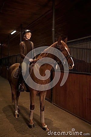 Smiling woman rancher riding out stable on horse Stock Photo