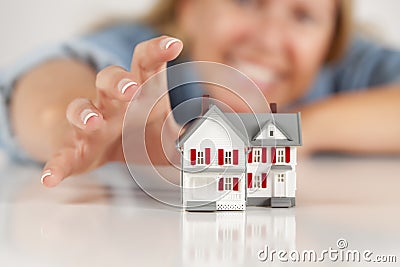 Smiling Woman Reaching for Model House on White Stock Photo