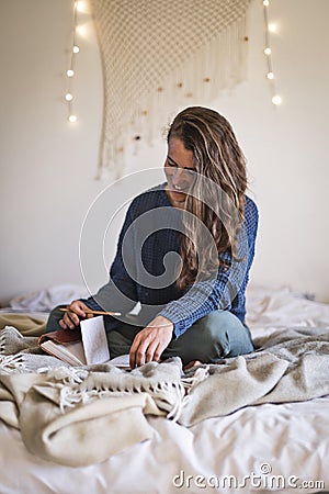 Smiling woman reading her diary on bed Stock Photo