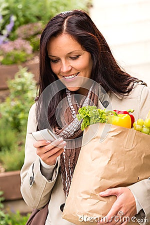 Smiling woman shopping vegetables mobile phone sms Stock Photo