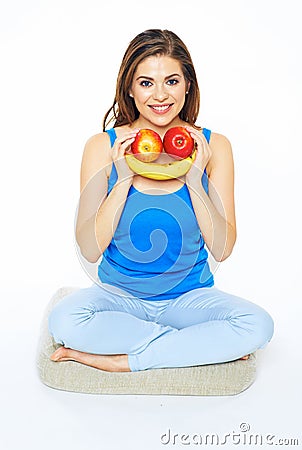 Smiling woman sitting on a floor in yoga pose, holding fruit sm Stock Photo