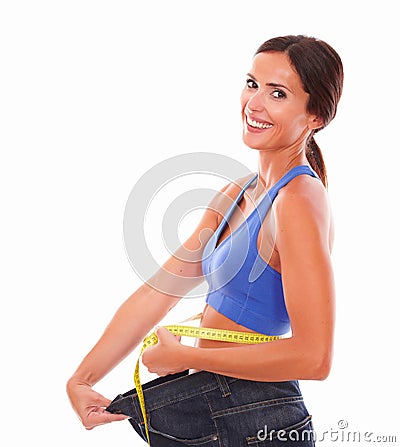 Smiling woman in sportswear pulling jeans on waist Stock Photo