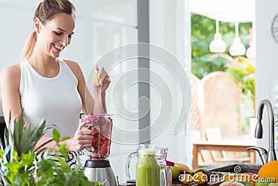 Smiling woman squeezing orange juice Stock Photo