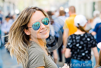 Smiling woman in sun glasses looking back in a city Stock Photo