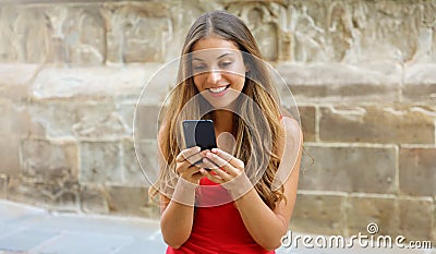 Smiling woman using mobile phone app to play video games online. City woman relaxing. Urban lifestyle. Banner crop for advertising Stock Photo