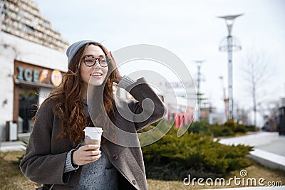 Smiling woman walking and drinking take away coffee outdoors Stock Photo