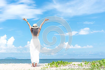 Smiling woman wearing fashion white dress summer walking on the sandy ocean beach, beautiful blue sky background. Happy woman enj Stock Photo