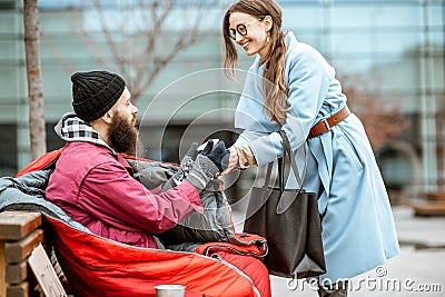 Woman giving a drink to a homeless beggar Stock Photo