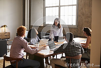 Smiling woman standing to address colleagues at a work meeting Stock Photo